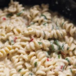 Crockpot Garlic Parmesan Chicken Pasta served with fresh herbs and Parmesan cheese.
