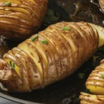 Hasselback potatoes sliced thinly, golden brown, garnished with herbs and served on a plate.