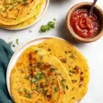 Delicious red lentil pancake served with fresh herbs and a drizzle of sauce