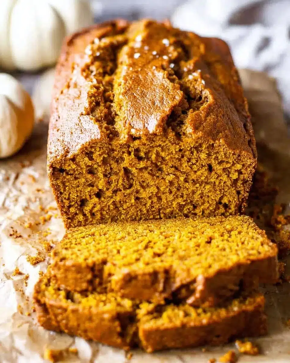 Sliced vanilla pudding pumpkin bread on a wooden table, showcasing its moist texture.