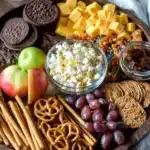 A beautifully arranged caramel apple charcuterie board with various toppings.