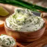 Cucumber cream cheese spread on a cracker with fresh herbs