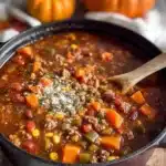 Bowl of Fall Harvest Chili with squash and sweet potato garnished with herbs.