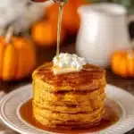 Stack of light and fluffy pumpkin spice pancakes topped with syrup and spices.