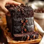 Moist chocolate pumpkin bread slice on a plate with chocolate drizzle and pumpkin seeds