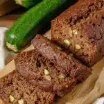 Moist zucchini bread loaf with fresh herbs and spices on a wooden table