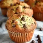 Freshly baked zucchini muffins with chocolate chips on a rustic wooden table