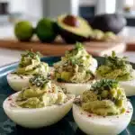 Plate of avocado deviled eggs garnished with herbs and spices