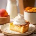 A slice of buttermilk pie topped with whipped cream and a cherry on a plate.
