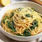 Delicious lemon spinach pasta dish garnished with fresh herbs and lemon zest.