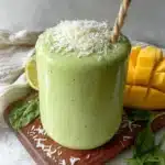 Mango spinach smoothie in a glass with fresh ingredients