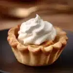 Muffin tin pumpkin pies on a decorative plate, perfect for fall desserts.