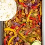 Sheet pan meal of chicken fajitas with peppers and onions ready to serve.