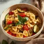 Delicious Tomato Zucchini Pasta served in a bowl with fresh herbs and Parmesan cheese