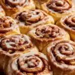 Homemade apple cinnamon rolls topped with icing on a wooden table