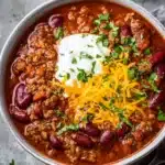 Delicious stovetop ground beef chili served in a bowl with toppings.