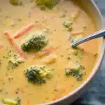 Bowl of creamy broccoli cheddar soup garnished with fresh broccoli florets.