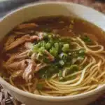 Bowl of homemade Chicken Noodle Soup with fresh vegetables and herbs