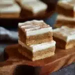 Cinnamon cookie bars topped with cream cheese frosting on a white plate