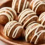 Cinnamon roll energy balls topped with cinnamon and icing, healthy snack alternative.