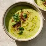 Bowl of creamy Vegan Zucchini Soup topped with herbs and spices