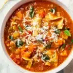 Bowl of veggie-loaded lasagna soup topped with fresh herbs and cheese