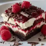 Delicious Chocolate Raspberry Cheesecake served on a plate with fresh raspberries.