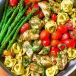 One-Pan Pesto Chicken with tortellini and mixed vegetables in a skillet.