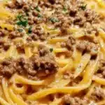 Creamy garlic butter pasta dish topped with ground beef and herbs