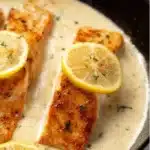Plate of creamy lemon salmon garnished with herbs