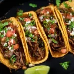 Crock Pot Street Tacos served on a wooden table with fresh toppings.