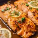 A delicious plate of honey garlic salmon garnished with herbs and served with vegetables.