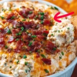 Bowl of irresistible crack dip served with tortilla chips on a wooden table
