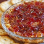 Delicious pepper jelly cheese dip served with crackers and fresh vegetables.