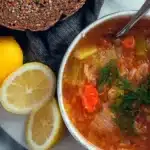 Bowl of healthy vegan cabbage soup with lentils served with herbs.
