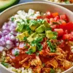 Chicken enchilada served in a bowl with cauliflower rice and toppings