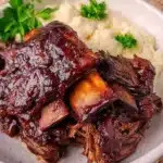 Delicious Crockpot BBQ Beef Ribs served with sauce and garnished with herbs
