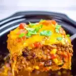 Crockpot beef enchilada casserole topped with cheese and fresh ingredients