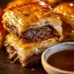 French Dip Squares served on a plate, garnished with herbs and dipping sauce.
