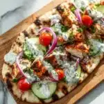 Delicious Greek Chicken Flatbread topped with fresh vegetables and herbs