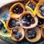 Mini Dutch baby pancakes with blueberry lemon compote topped on a plate
