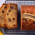 Slice of moist banana bread with chocolate chips and nuts on a wooden table