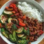 Spicy ground beef stir-fry bowl with garlic vegetables and rice