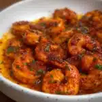 Delicious spicy shrimp garnished with herbs and spices served on a plate.