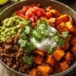 A vibrant sweet potato taco bowl garnished with fresh avocado and cilantro.