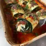 Plate of Zucchini Rollatini filled with cheese and herbs, garnished with tomato sauce