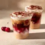 Refreshing Cherry Vanilla Iced Latte served in a glass with ice and cherry garnish.