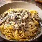 Creamy mushroom pasta sauce served over spaghetti garnished with parsley.