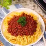 Crockpot spaghetti and meat sauce served in a bowl with fresh basil.