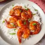 Delicious ketchup shrimp served on a plate, garnished with herbs.